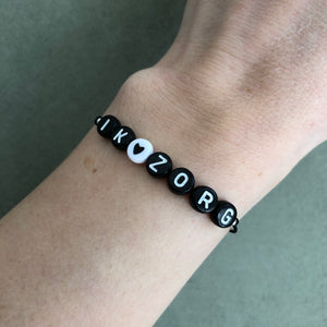Armbandje Ik zorg Zwart wit met bedeltje
